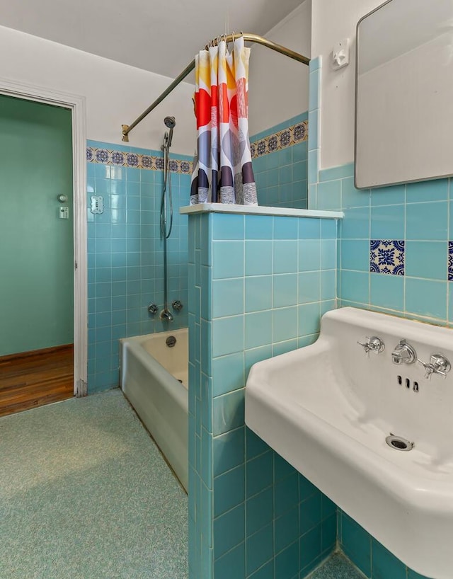 bathroom with sink, tile walls, and shower / bath combo with shower curtain