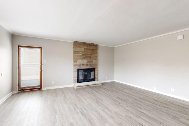unfurnished living room featuring a stone fireplace and light hardwood / wood-style flooring