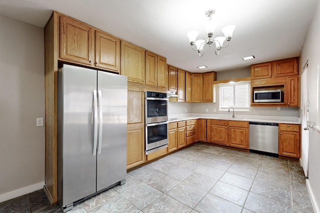 kitchen with hanging light fixtures, appliances with stainless steel finishes, sink, and a notable chandelier