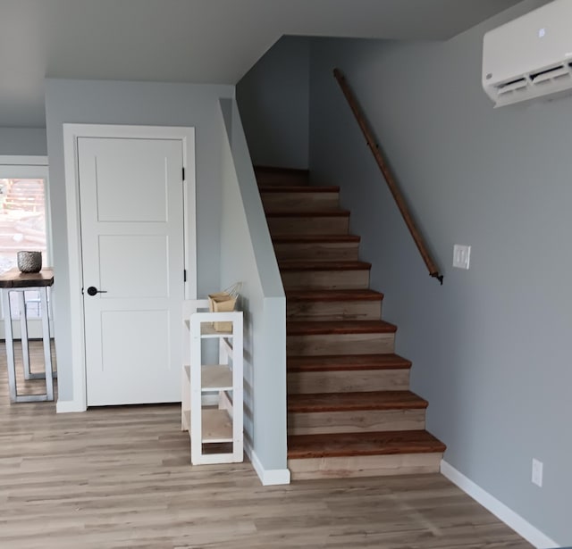 staircase featuring wood-type flooring and an AC wall unit