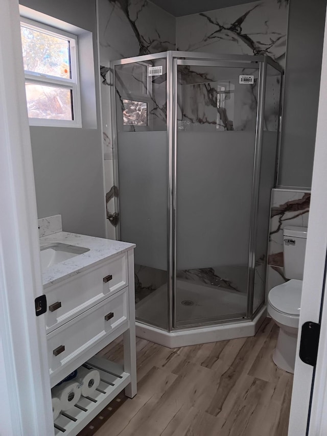 bathroom featuring vanity, wood-type flooring, an enclosed shower, and toilet