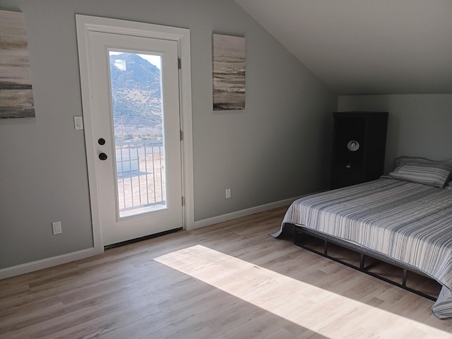 bedroom with access to exterior, vaulted ceiling, and light wood-type flooring