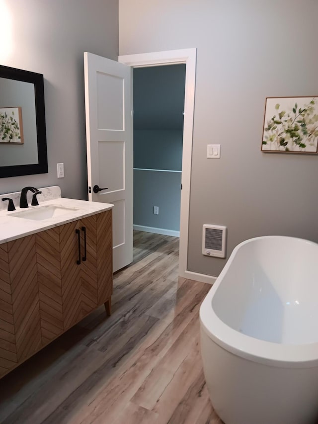 bathroom with a bathing tub, hardwood / wood-style floors, and vanity