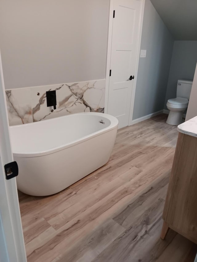 bathroom with vanity, a bath, wood-type flooring, and toilet