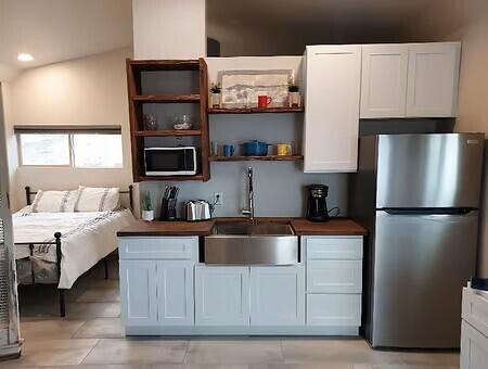 kitchen with white cabinetry, lofted ceiling, sink, and stainless steel fridge