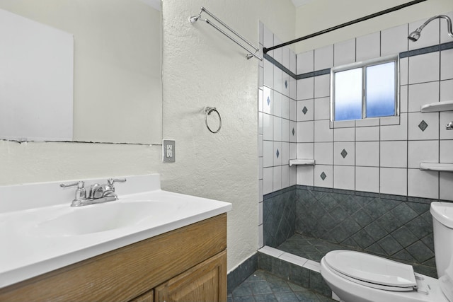 bathroom with vanity, toilet, and a tile shower