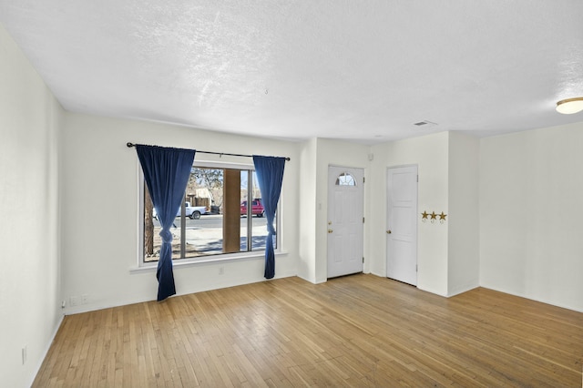 empty room featuring a textured ceiling and light hardwood / wood-style floors