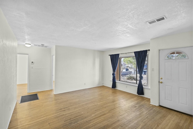 entryway with a textured ceiling and light wood-type flooring