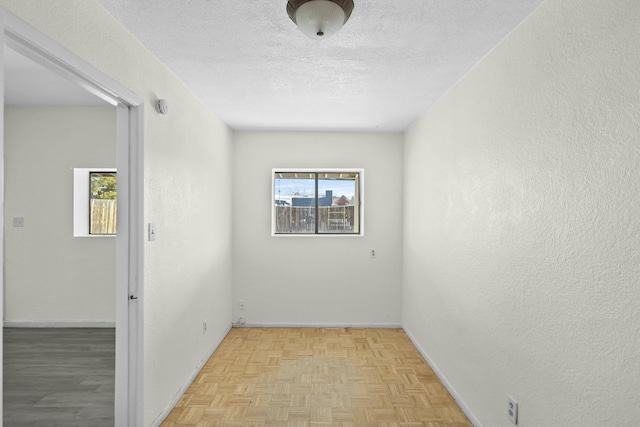 unfurnished room with light parquet flooring and a textured ceiling