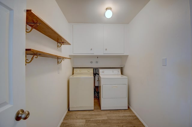 laundry area with cabinets, separate washer and dryer, and light hardwood / wood-style floors