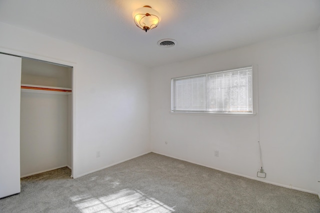 unfurnished bedroom with a closet and light carpet