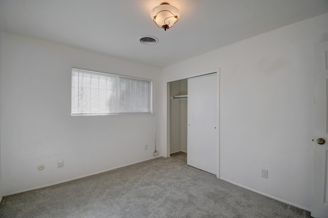 unfurnished bedroom with light colored carpet and a closet