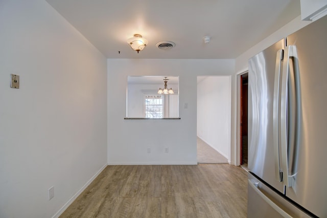 unfurnished dining area featuring a chandelier and light wood-type flooring