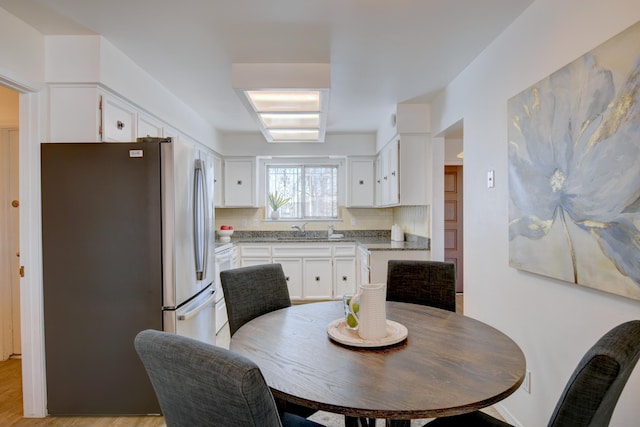 kitchen with white cabinetry, sink, backsplash, dark stone counters, and white appliances