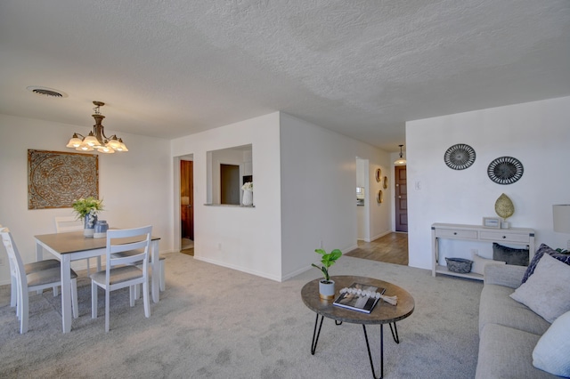 carpeted empty room with a textured ceiling and a chandelier