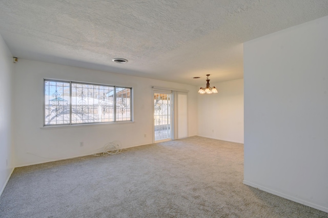 unfurnished room with carpet flooring, a notable chandelier, and a textured ceiling