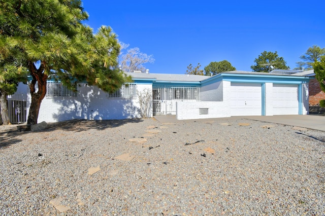 ranch-style home with driveway, brick siding, an attached garage, and fence