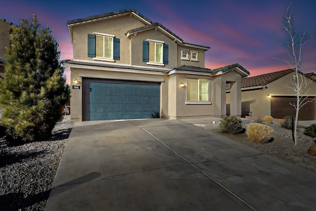 traditional-style home featuring driveway, a tiled roof, a garage, and stucco siding