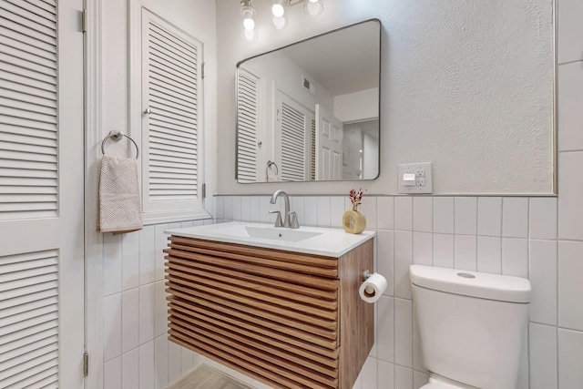 bathroom featuring vanity, toilet, and tile walls