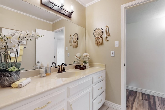 bathroom featuring crown molding, vanity, baseboards, and wood finished floors