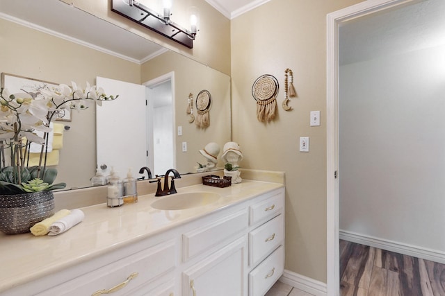 bathroom featuring baseboards, ornamental molding, wood finished floors, and vanity