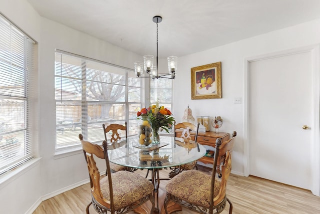 dining space with a chandelier, light wood-style flooring, and baseboards
