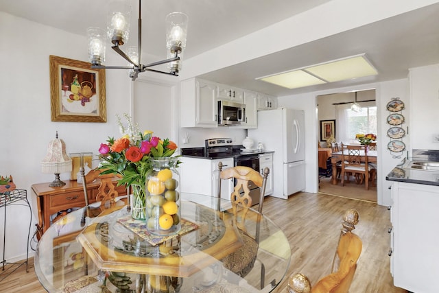 dining space featuring light wood-style flooring and an inviting chandelier