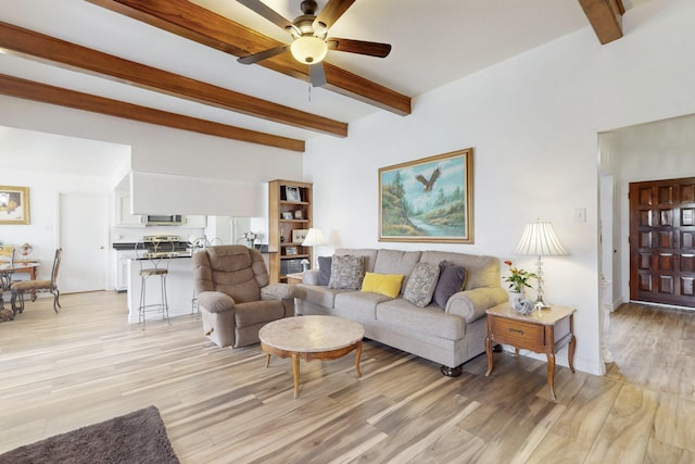 living room featuring light wood finished floors, ceiling fan, and beamed ceiling