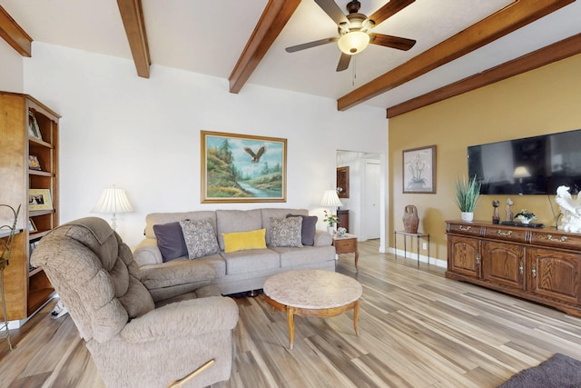 living area with baseboards, beamed ceiling, light wood-style flooring, and a ceiling fan