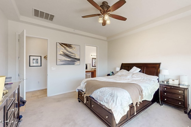 carpeted bedroom with ensuite bath and ceiling fan