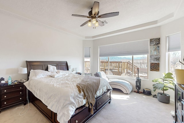 carpeted bedroom with ceiling fan, a raised ceiling, and a textured ceiling