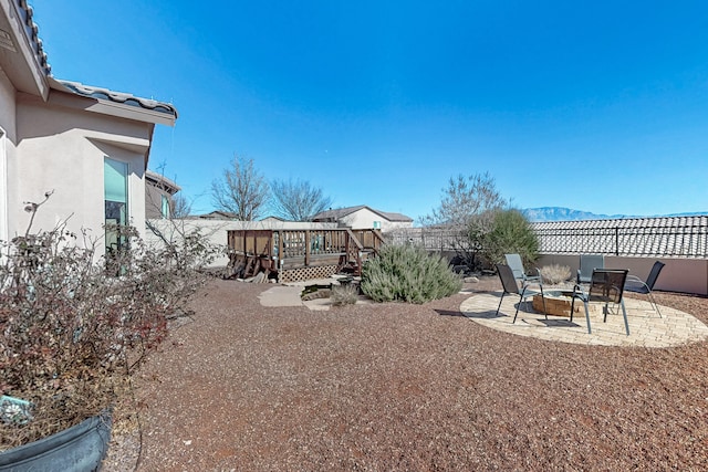 view of yard with an outdoor fire pit, a deck with mountain view, and a patio