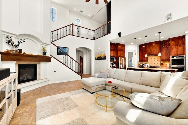 836 Mesa Roja Trl NE, Rio Rancho, NM 87144 - living room with stairs, a towering ceiling, arched walkways, light stone finish floors, and a glass covered fireplace