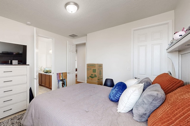 bedroom featuring a textured ceiling and ensuite bath