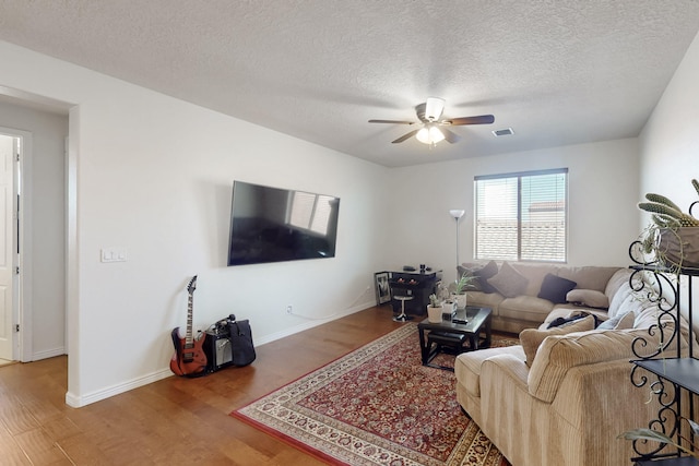 living room with hardwood / wood-style flooring, a textured ceiling, and ceiling fan