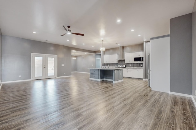 kitchen featuring a center island with sink, decorative light fixtures, light wood-type flooring, and white cabinets