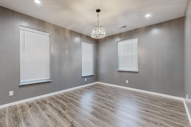 unfurnished room featuring a notable chandelier and wood-type flooring