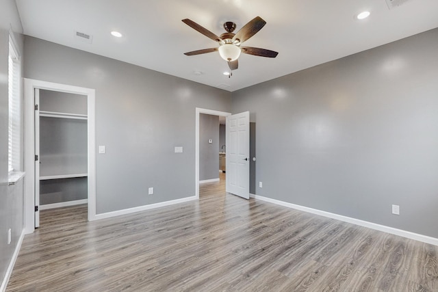 unfurnished bedroom featuring ceiling fan, light hardwood / wood-style flooring, a closet, and a spacious closet