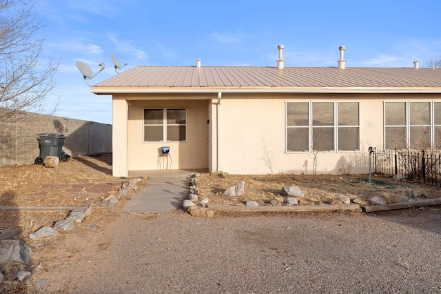 view of front of home featuring metal roof, fence, and stucco siding