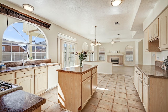 kitchen featuring a kitchen island, pendant lighting, sink, white dishwasher, and light brown cabinets