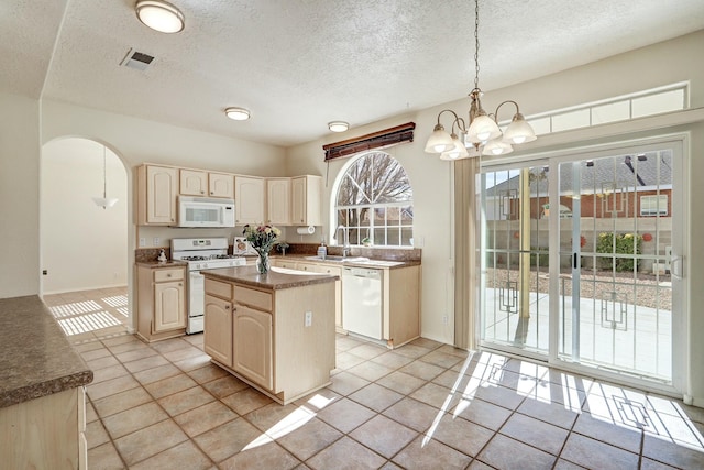 kitchen featuring sink, decorative light fixtures, light tile patterned floors, a kitchen island, and white appliances