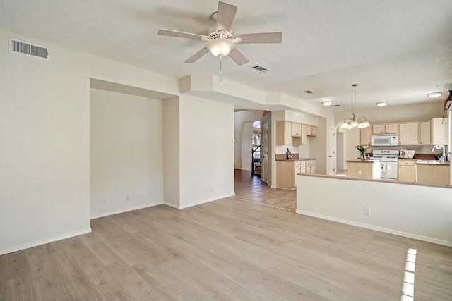 kitchen featuring sink, white appliances, light hardwood / wood-style flooring, light brown cabinetry, and ceiling fan with notable chandelier