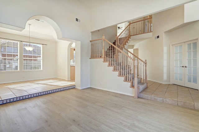 foyer with a high ceiling, light hardwood / wood-style floors, and french doors