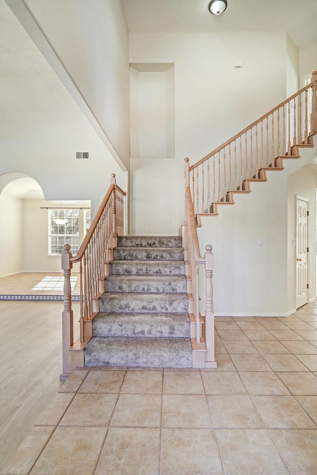 stairs featuring tile patterned flooring and a towering ceiling