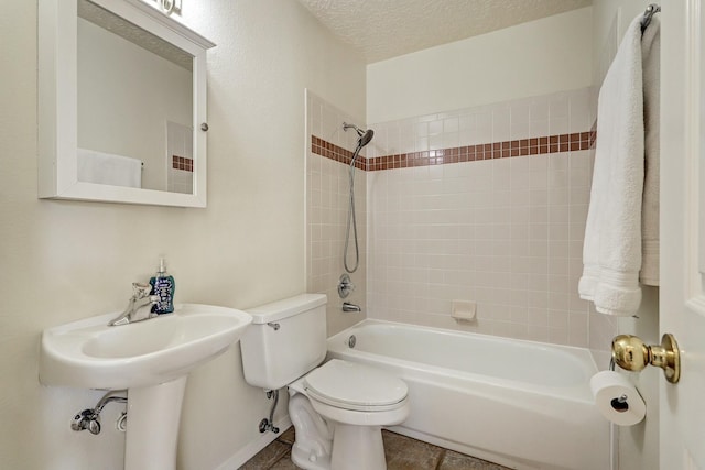 bathroom featuring toilet, tiled shower / bath combo, and a textured ceiling