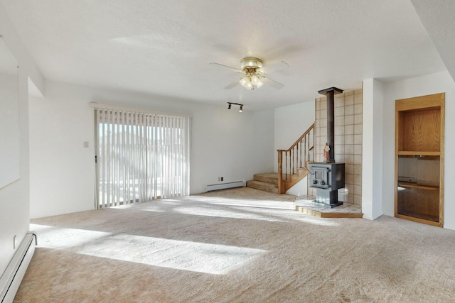 unfurnished living room featuring ceiling fan, a baseboard heating unit, light colored carpet, and a textured ceiling