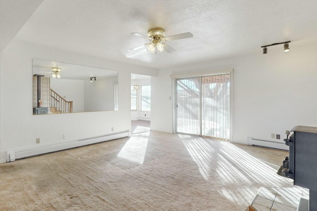 carpeted living room with a baseboard radiator, a wood stove, ceiling fan, and a textured ceiling