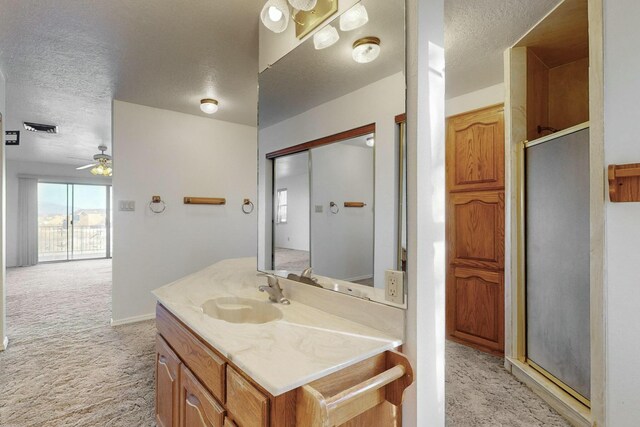 bathroom featuring vanity, ceiling fan, a textured ceiling, and a shower with shower door