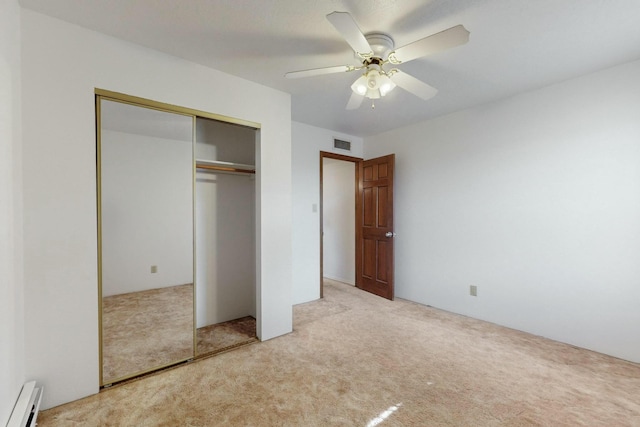 unfurnished bedroom featuring baseboard heating, light colored carpet, ceiling fan, and a closet