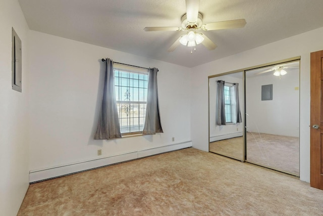 unfurnished bedroom featuring light carpet, a baseboard heating unit, multiple windows, and a closet